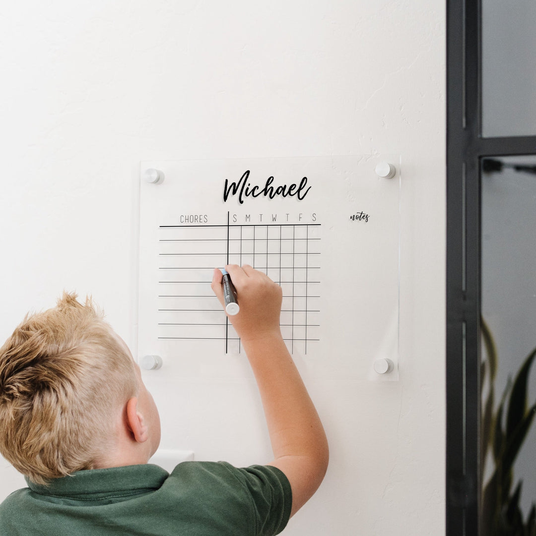 A Dry-erase acrylic chore chart hanging on the wall