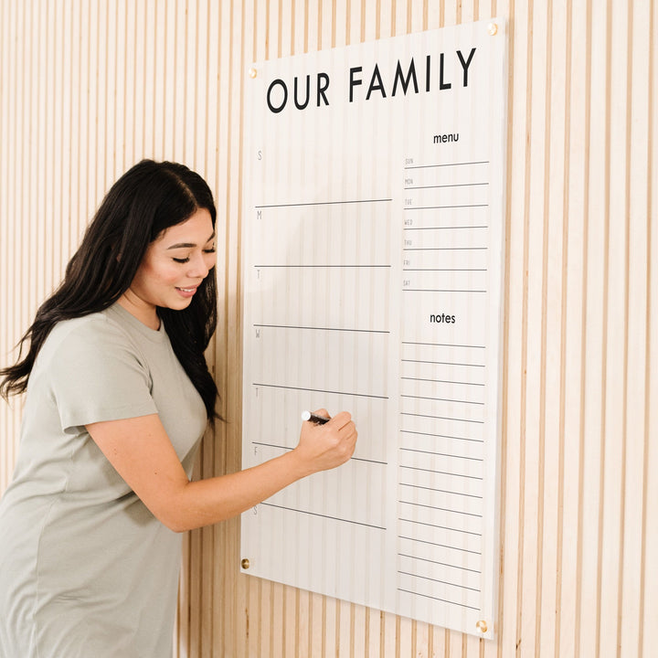 A Dry-erase weekly calender made of acrylic hanging on the wall