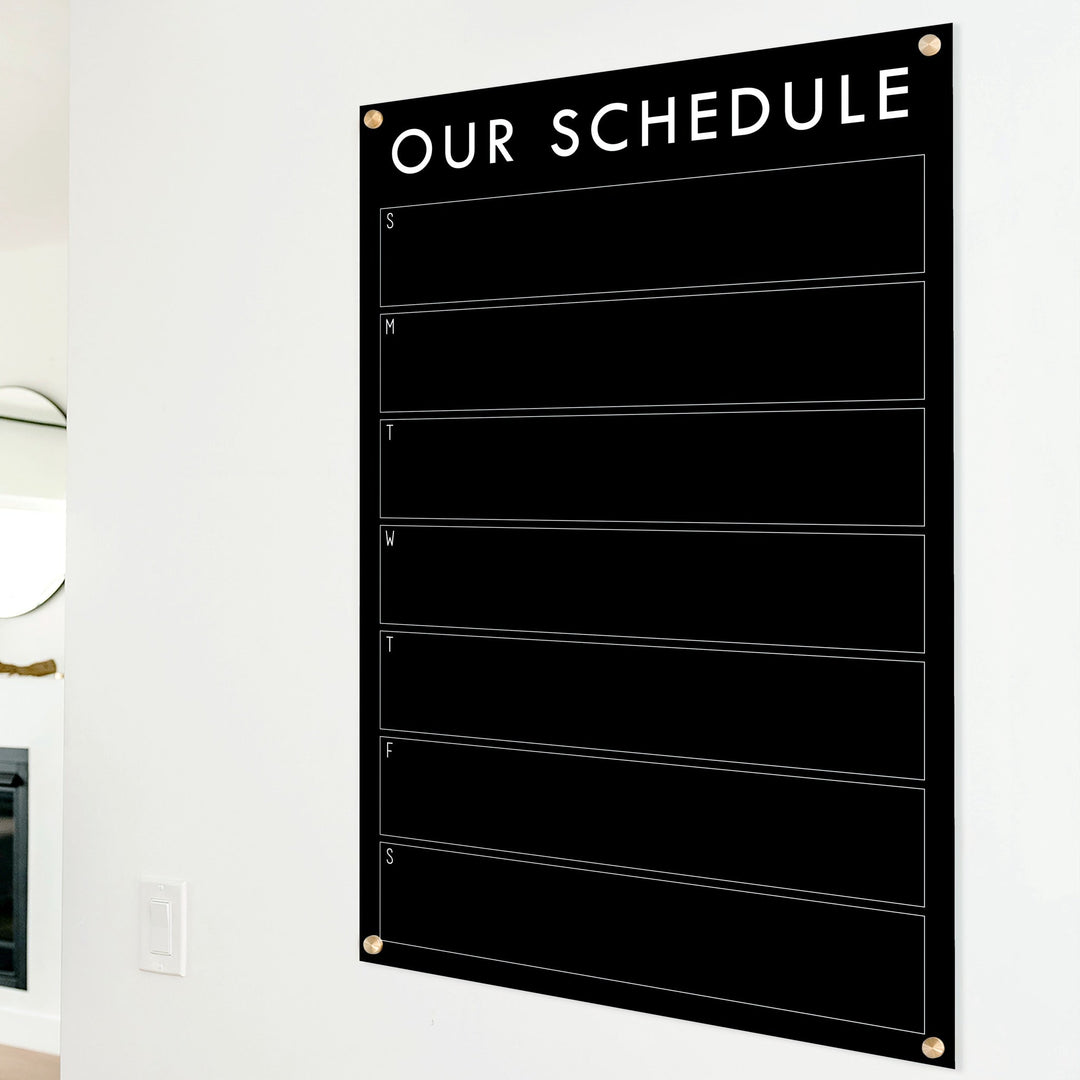 A Dry-erase weekly calender made of acrylic hanging on the wall