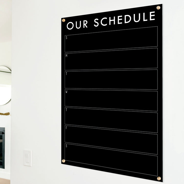 A Dry-erase weekly calender made of acrylic hanging on the wall