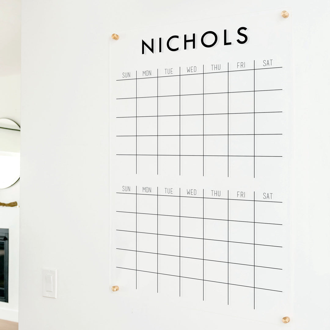 A Dry-erase acrylic calendar with a two month design format hanging on the wall