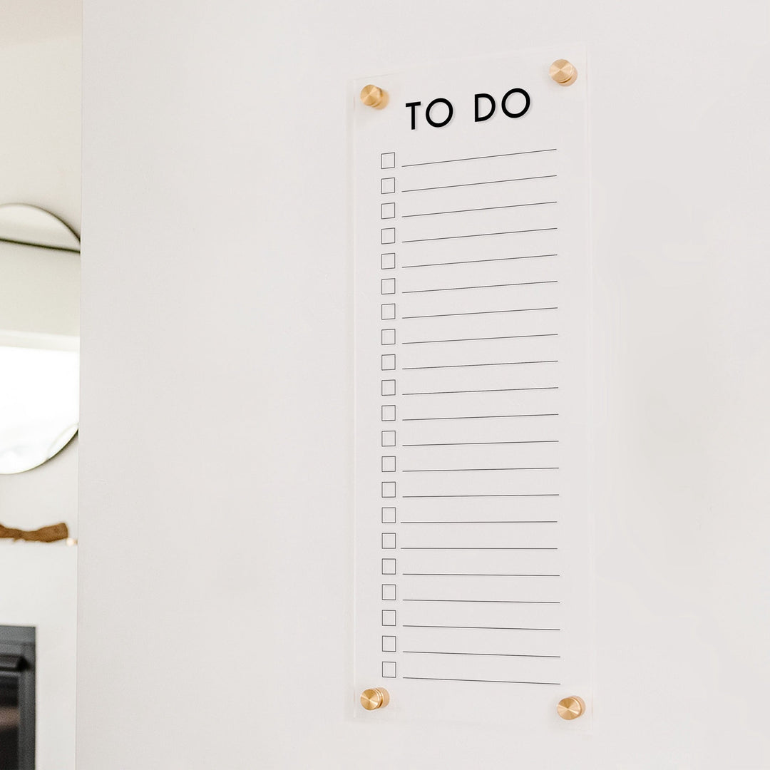 A dry-erase to do list made of acrylic hanging on the wall