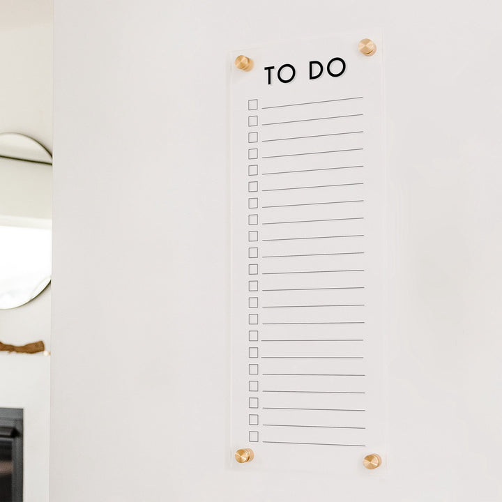 A dry-erase to do list made of acrylic hanging on the wall