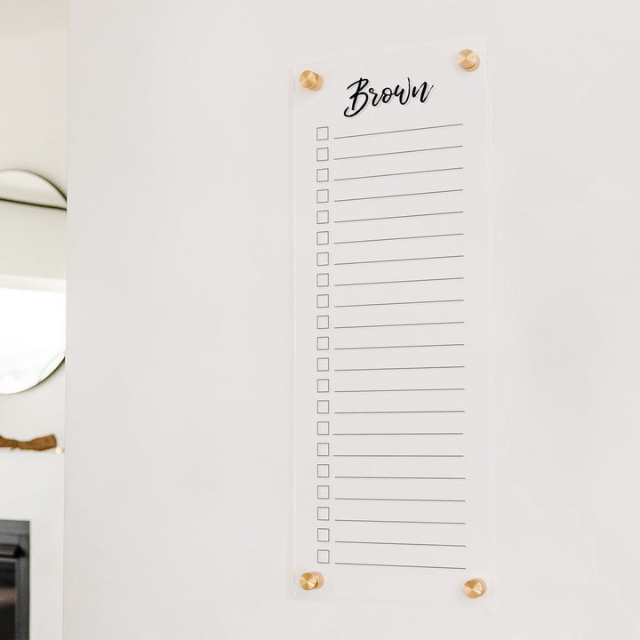 A dry-erase to do list made of acrylic hanging on the wall