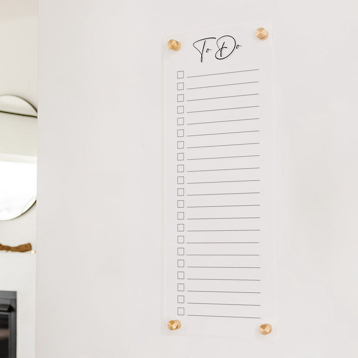 A dry-erase to do list made of acrylic hanging on the wall