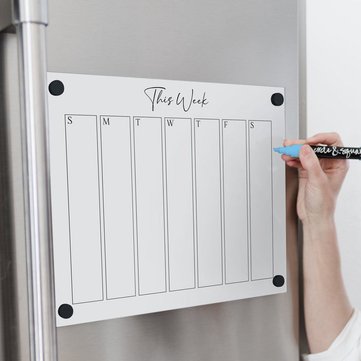 A Dry-erase weekly calender made of magnetic acrylic hanging on the fridge