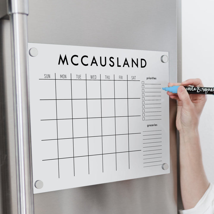 A Dry-erase monthly calender made of magnetic acrylic hanging on the fridge