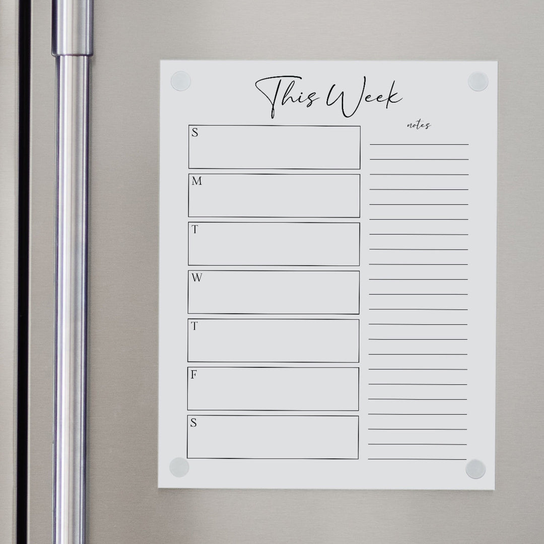 A skinny dry-erase weekly calender made of magnetic acrylic hanging on the fridge