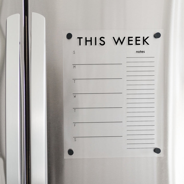 A Dry-erase weekly calender made of magnetic acrylic hanging on the fridge