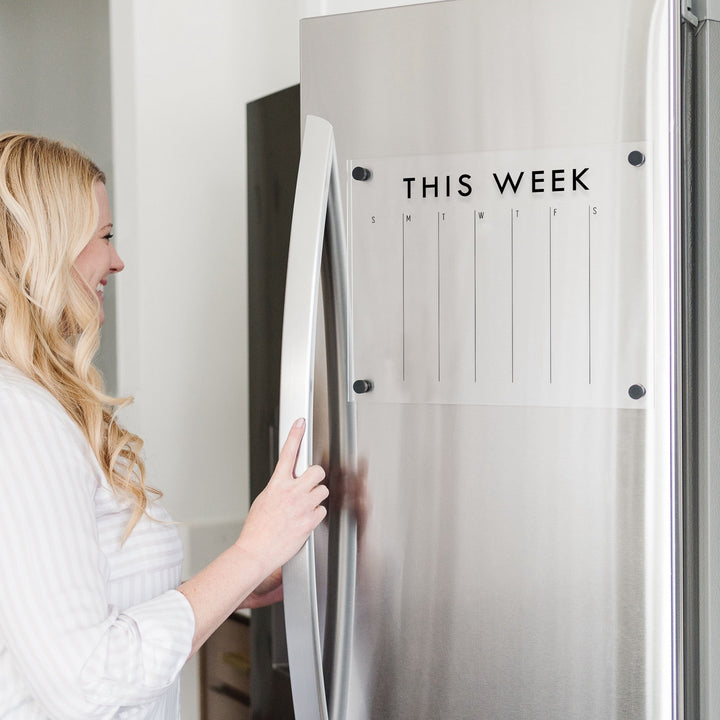 A Dry-erase weekly calender made of magnetic acrylic hanging on the fridge