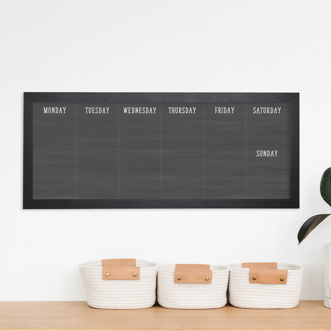A framed slim whiteboard weekly calender hanging on the wall