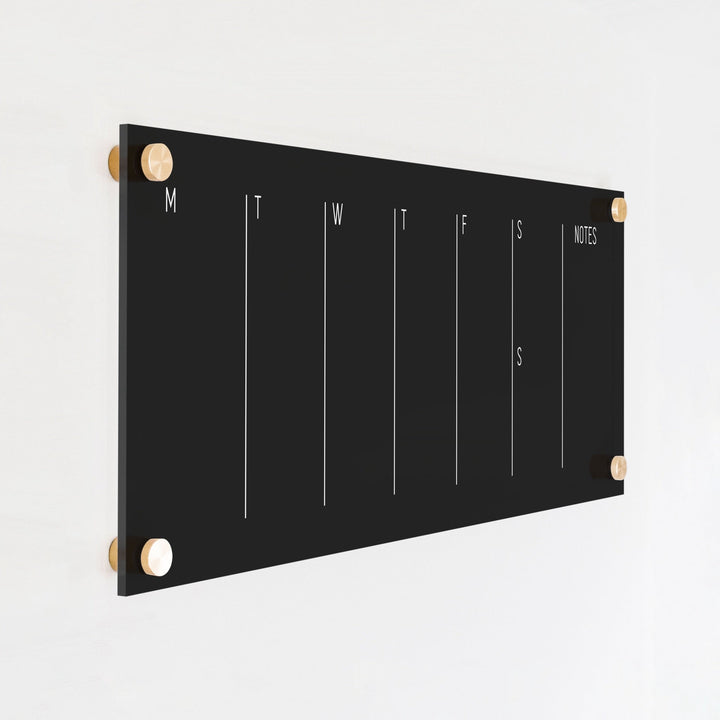 A skinny dry-erase weekly calender made of acrylic hanging on the wall