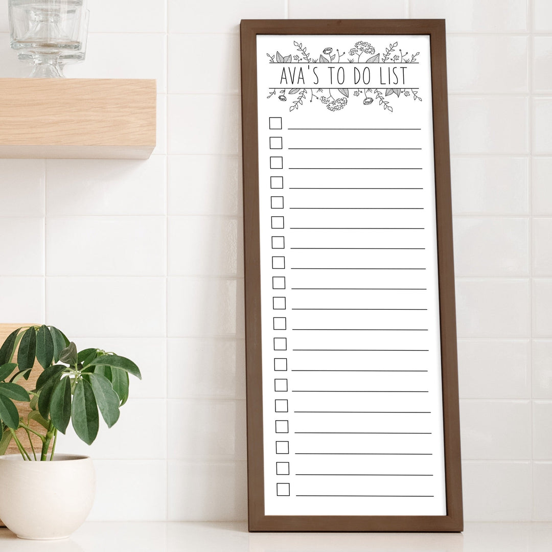 A framed whiteboard to do list hanging on the wall