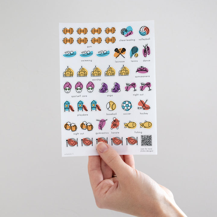 a hand holds a sheet of reusable schedule stickers