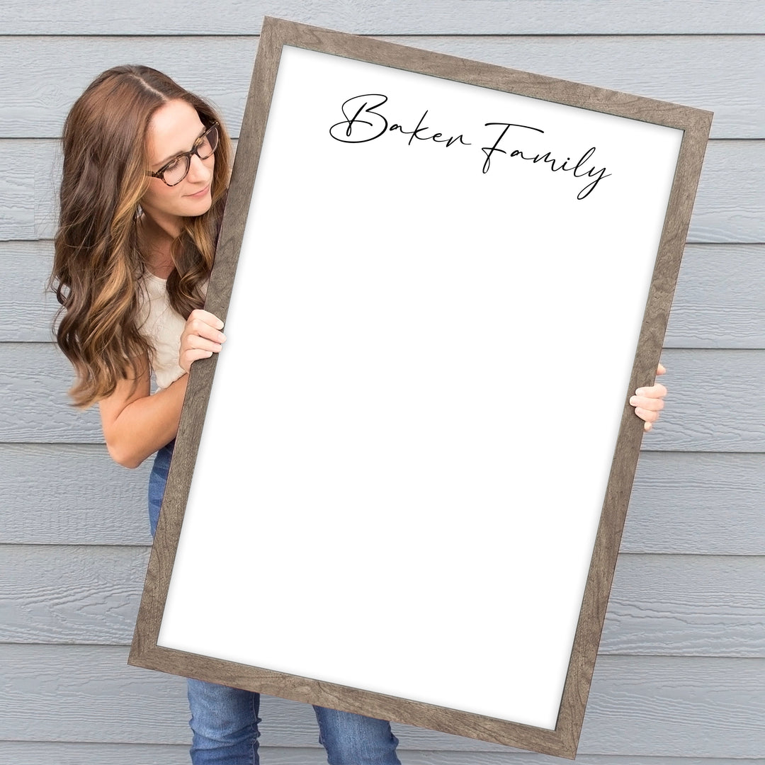 A framed whiteboard calendar with a two month design format hanging on the wall