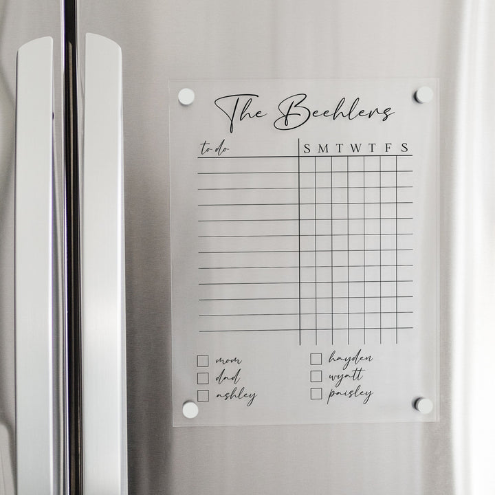 A Dry-erase acrylic chore chart hanging on the fridge