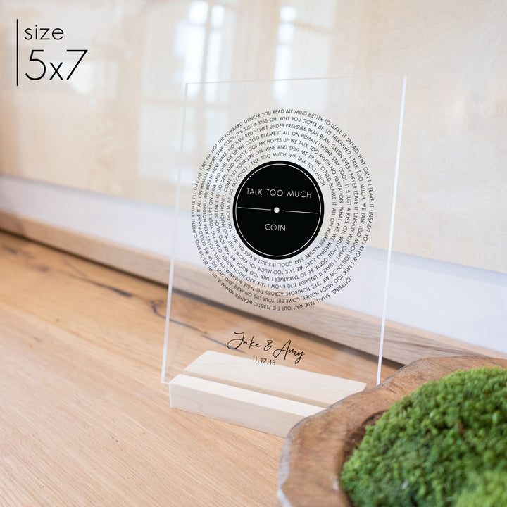 A 5x7 custom wedding gift with a record design printed on clear acrylic. Personalized titles, lyrics, and are dates are also shown.