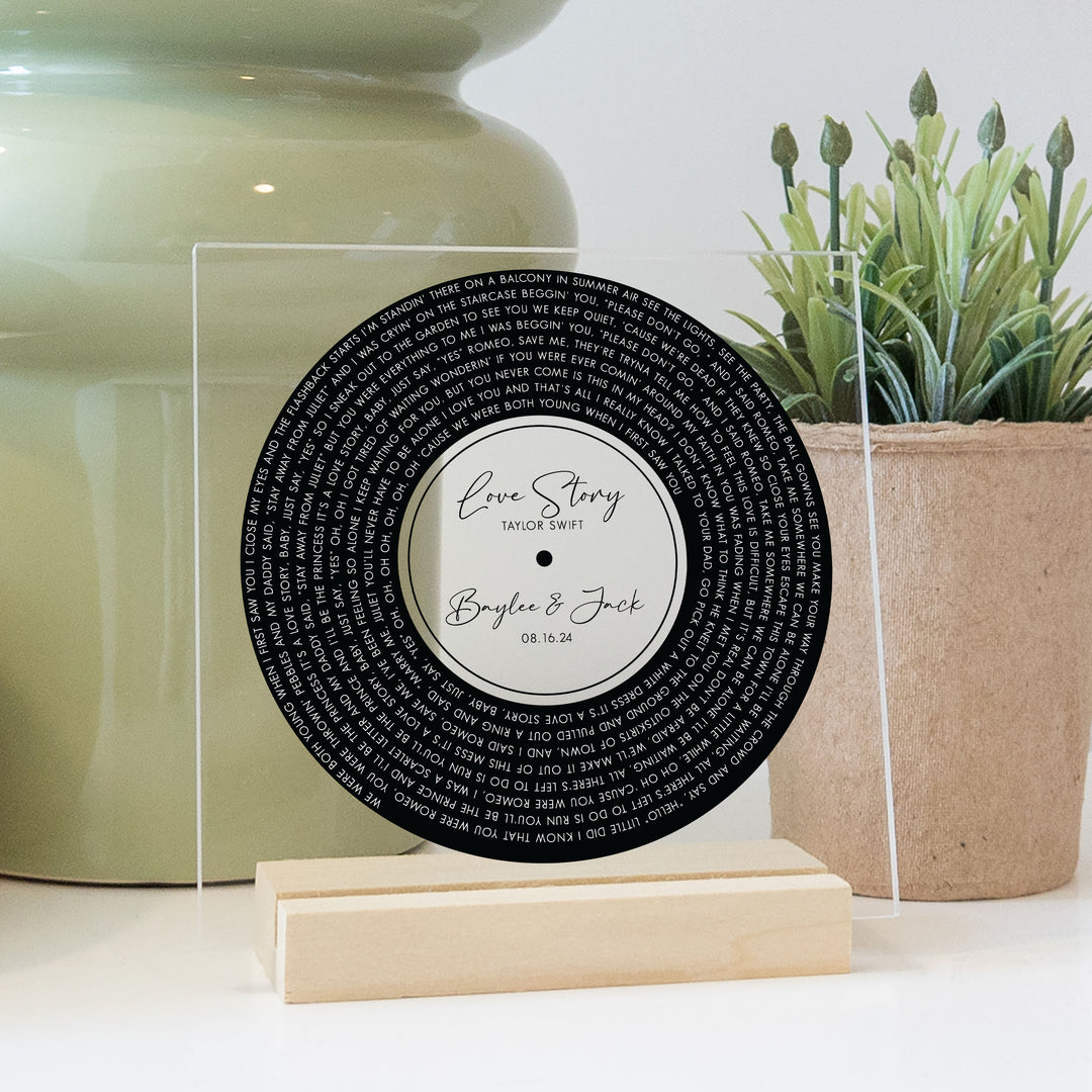 Record wedding decor sign with custom titles and lyrics printed on clear acrylic.