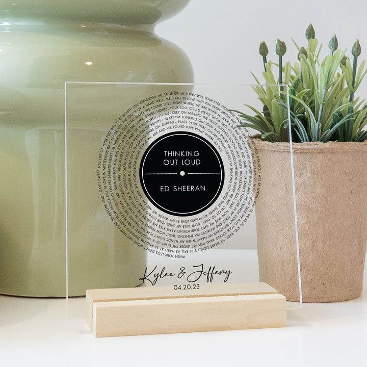 A clear acrylic home decor keepsake with a record design printed on it. Features custom titles and lyrics.