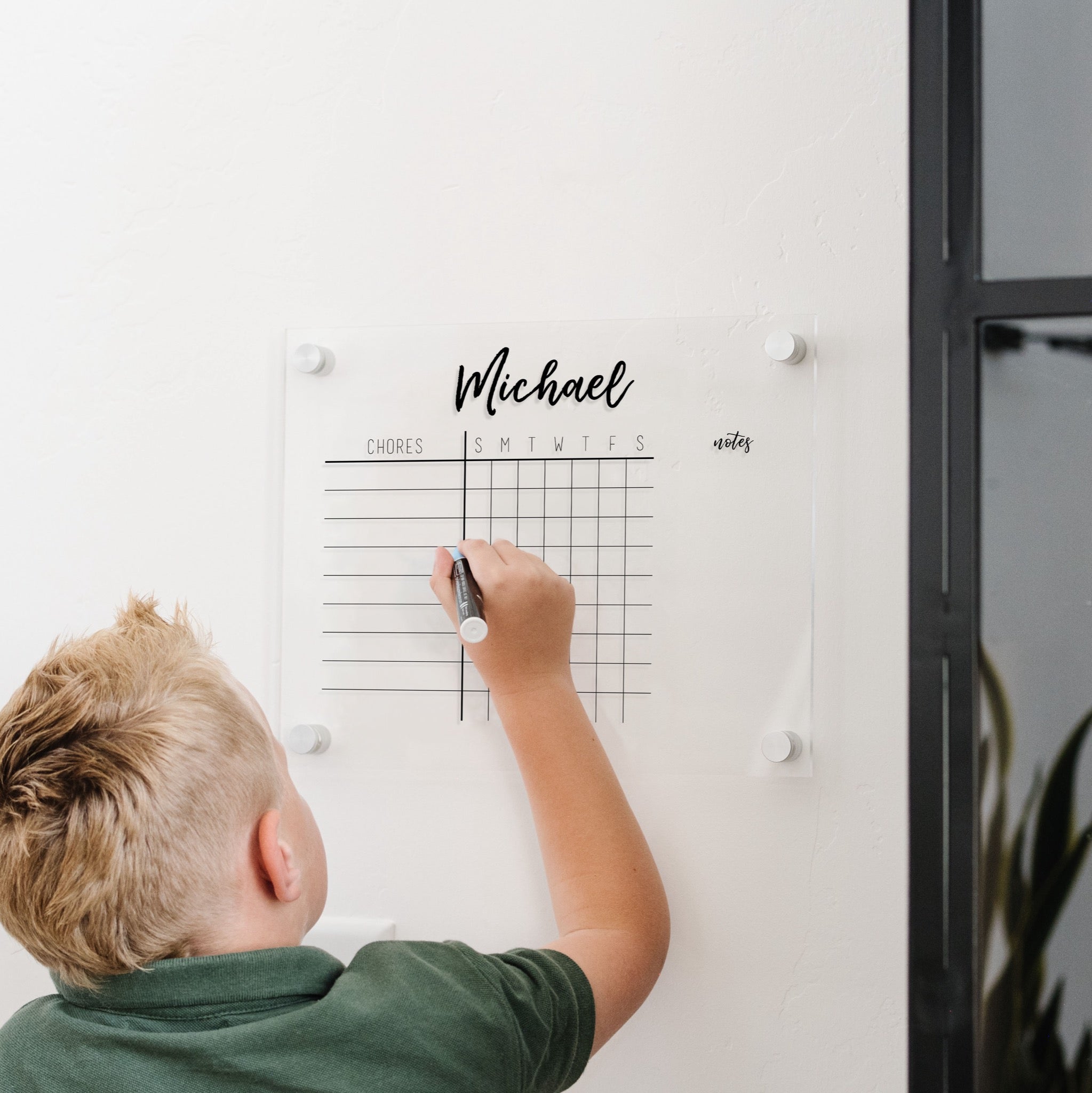 A Dry-erase acrylic chore chart hanging on the wall