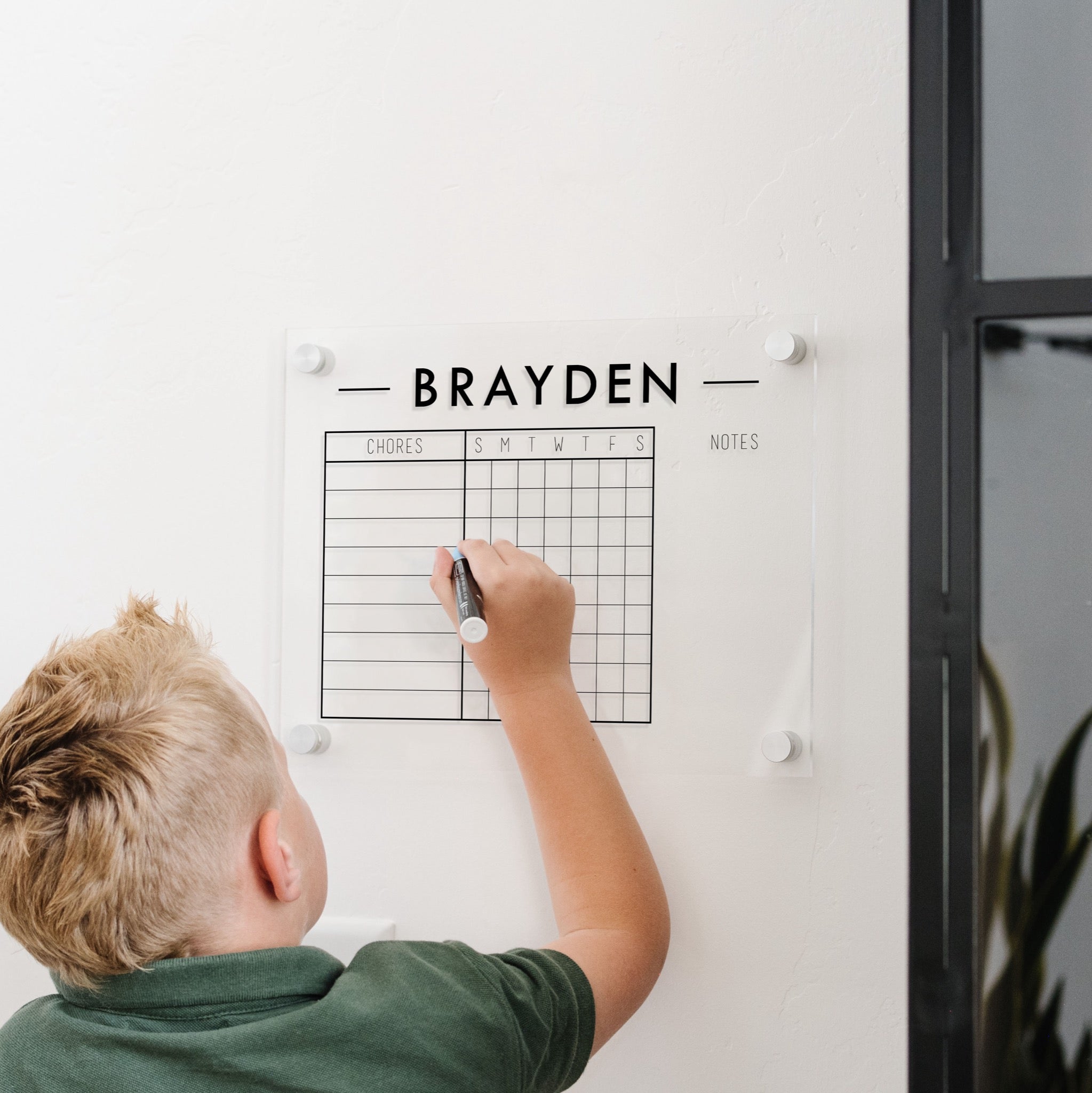 A Dry-erase acrylic chore chart hanging on the wall