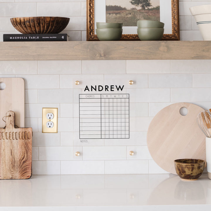A Dry-erase acrylic chore chart hanging on the wall