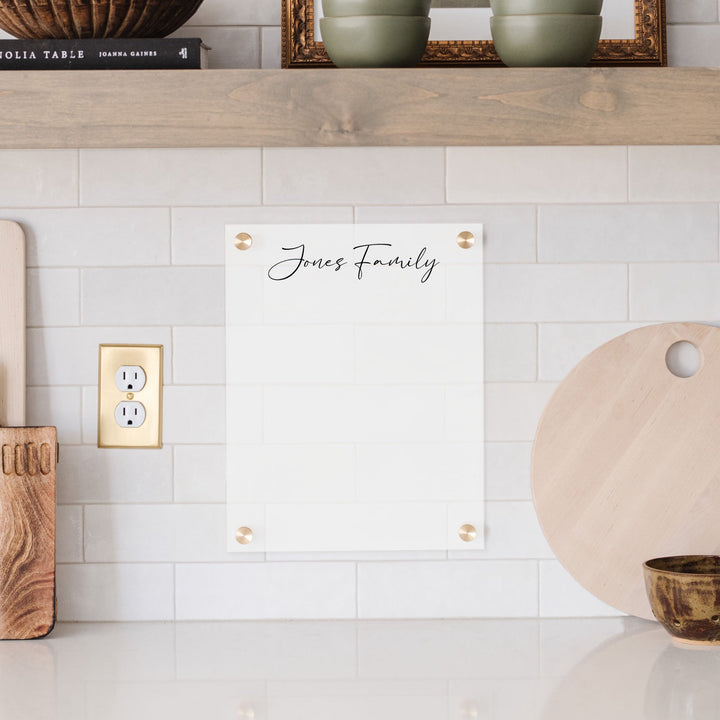 A dry-erase board made of clear acrylic with a custom title up top