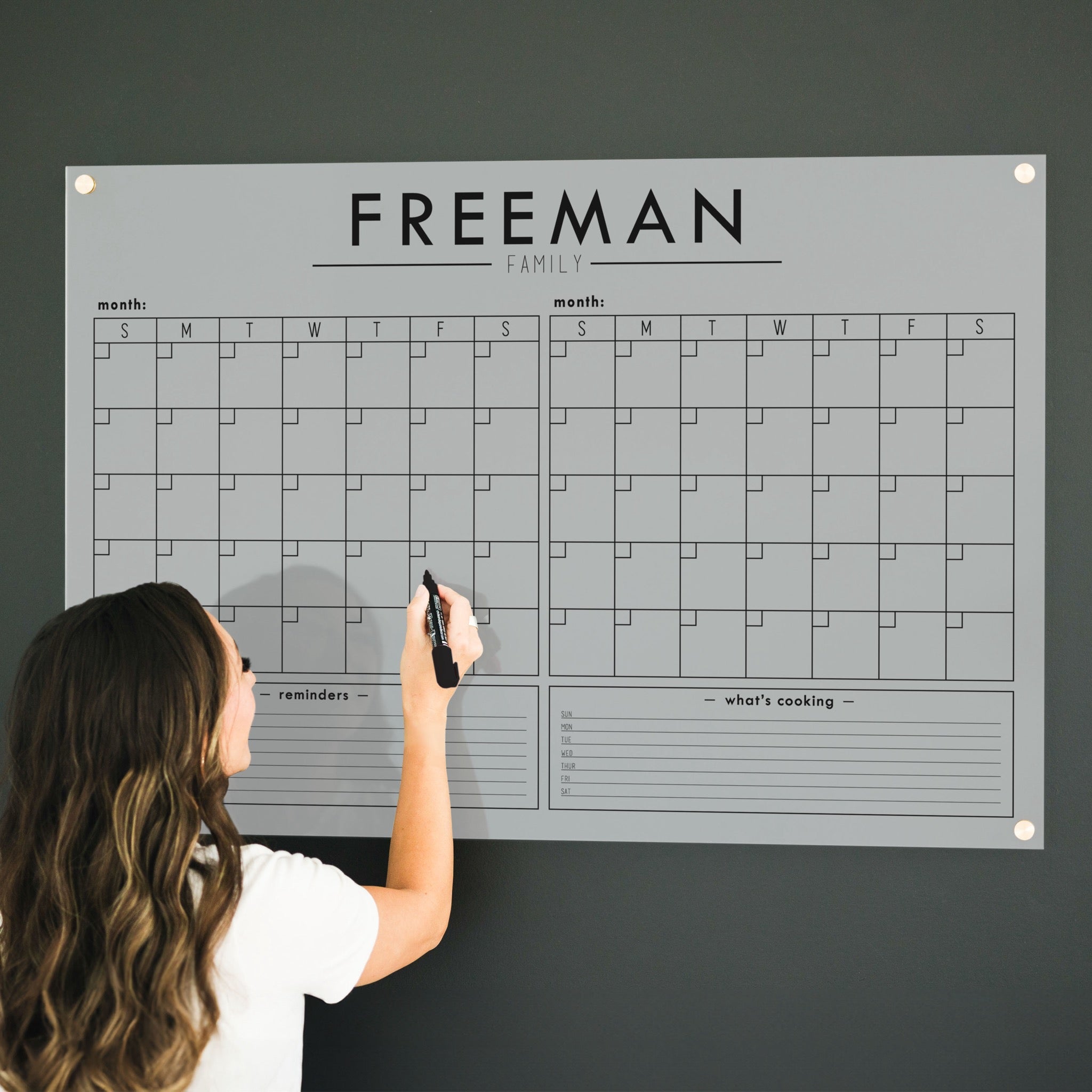 A Dry-erase acrylic calendar with a two month design format hanging on the wall