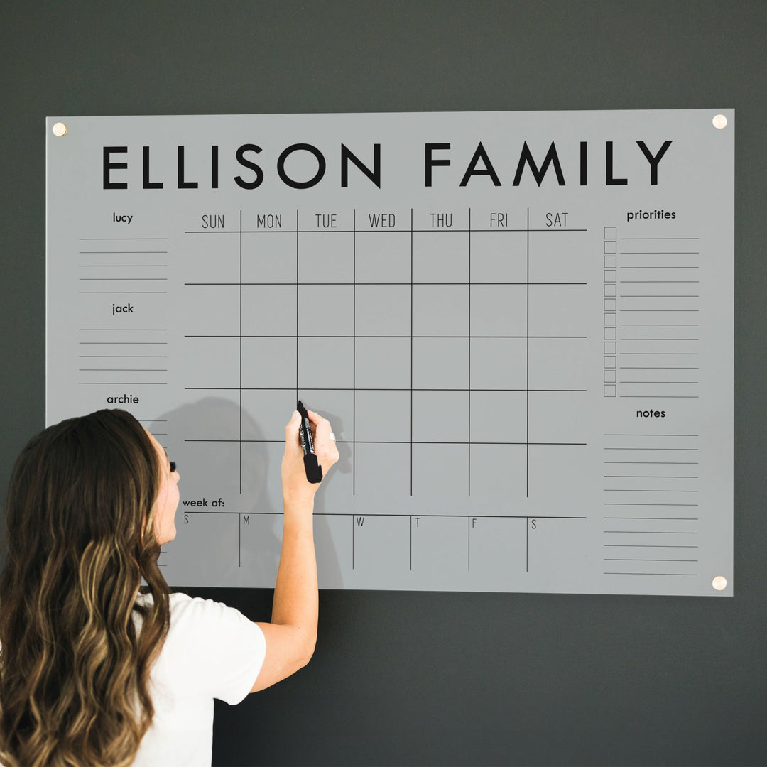 A Dry-erase calendar with a monthly and weekly format made of acrylic hanging on the wall