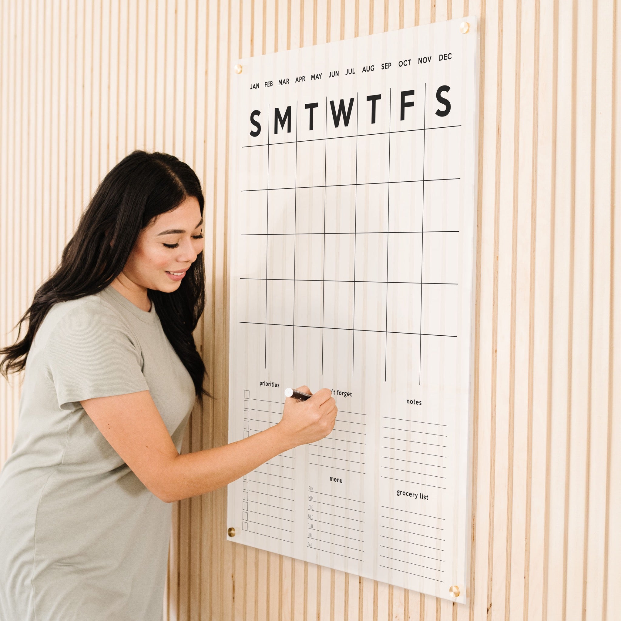 A Dry-erase family command center made of acrylic hanging on the wall