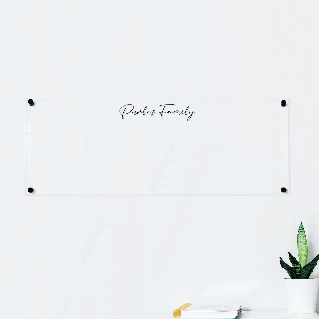 A dry-erase board made of clear acrylic with a custom title up top