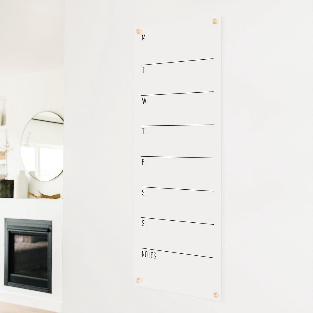 A skinny dry-erase weekly calender made of acrylic hanging on the wall