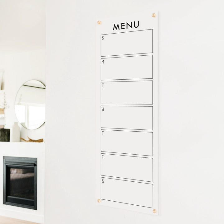 A skinny dry-erase weekly calender made of acrylic hanging on the wall