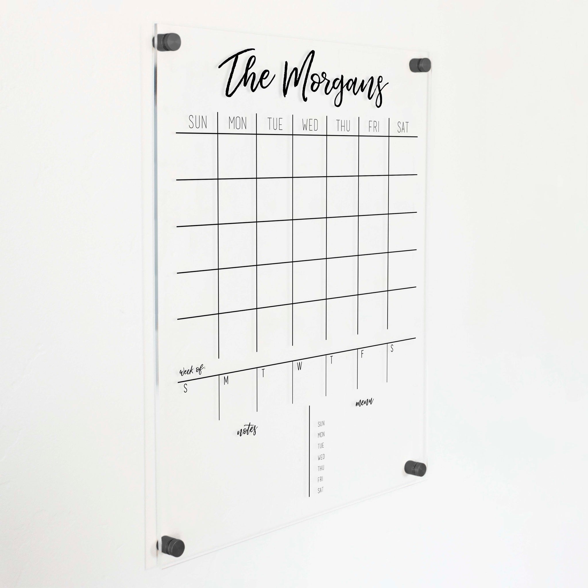 A Dry-erase calendar with a monthly and weekly format made of acrylic hanging on the wall