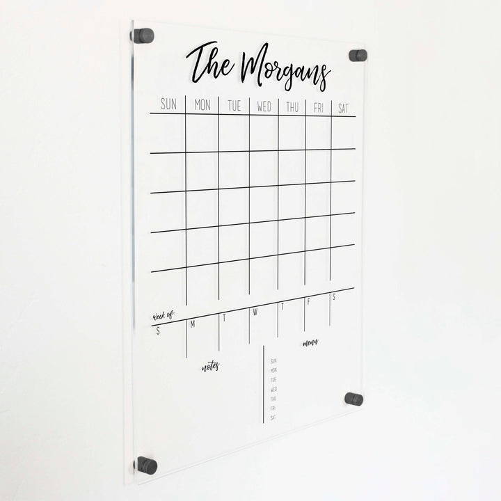 A Dry-erase calendar with a monthly and weekly format made of acrylic hanging on the wall