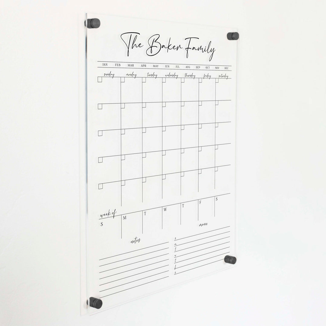 A Dry-erase calendar with a monthly and weekly format made of acrylic hanging on the wall