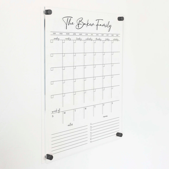 A Dry-erase calendar with a monthly and weekly format made of acrylic hanging on the wall