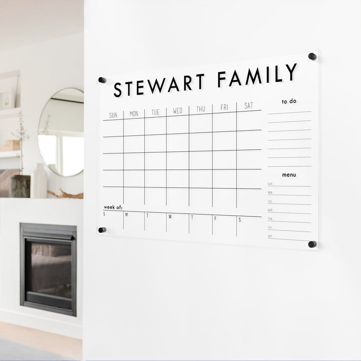 A Dry-erase calendar with a monthly and weekly format made of acrylic hanging on the wall
