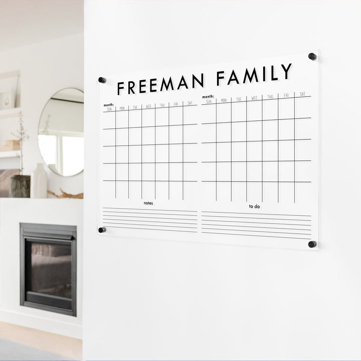 A Dry-erase acrylic calendar with a two month design format hanging on the wall