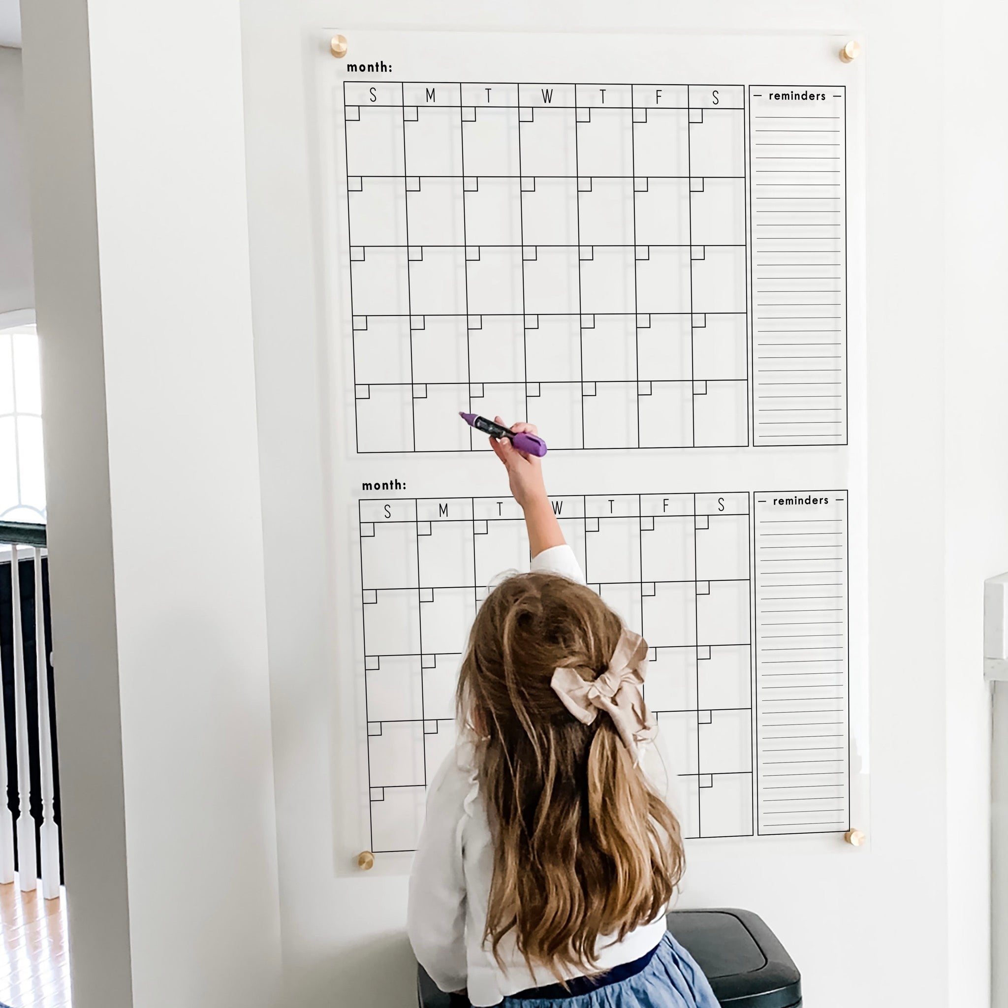 A Dry-erase acrylic calendar with a two month design format hanging on the wall