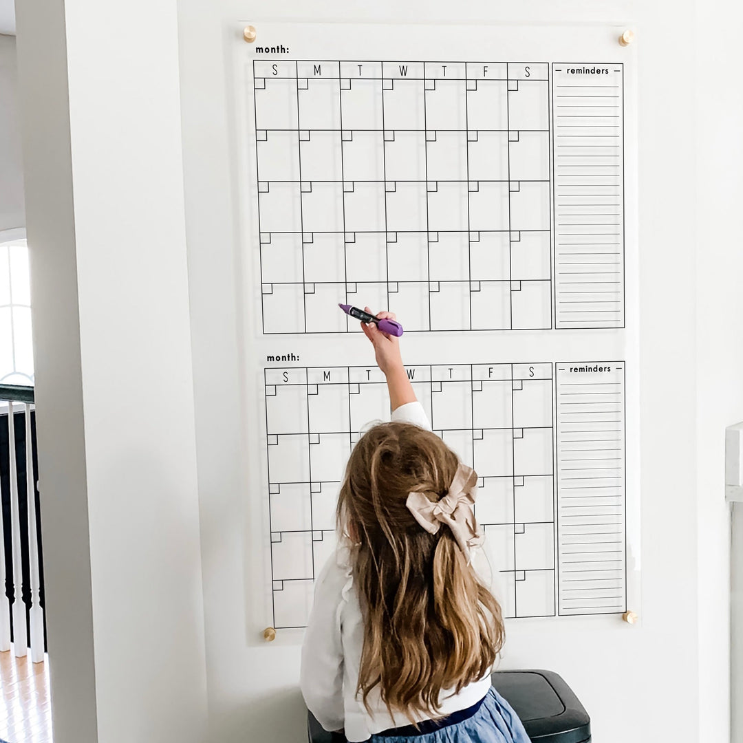 A Dry-erase acrylic calendar with a two month design format hanging on the wall