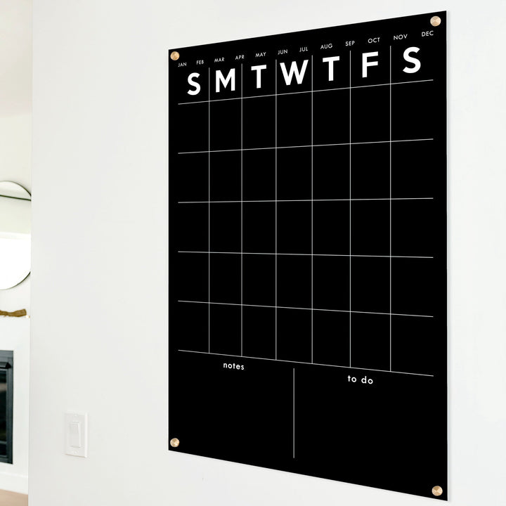 A Dry-erase monthly calender made of acrylic hanging on the wall