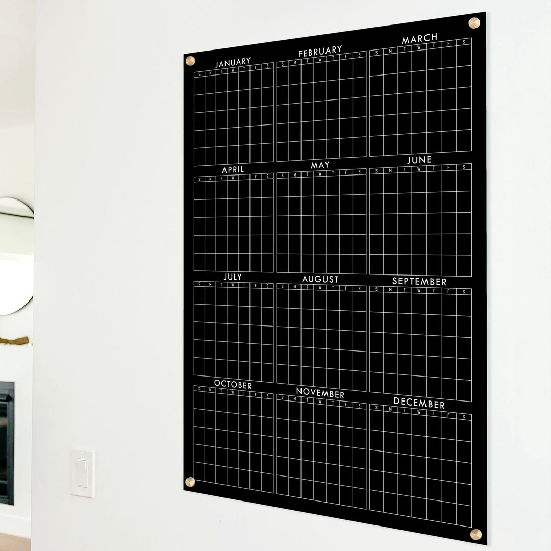 A dry-erase yearly calendar made of acrylic hanging up on the wall