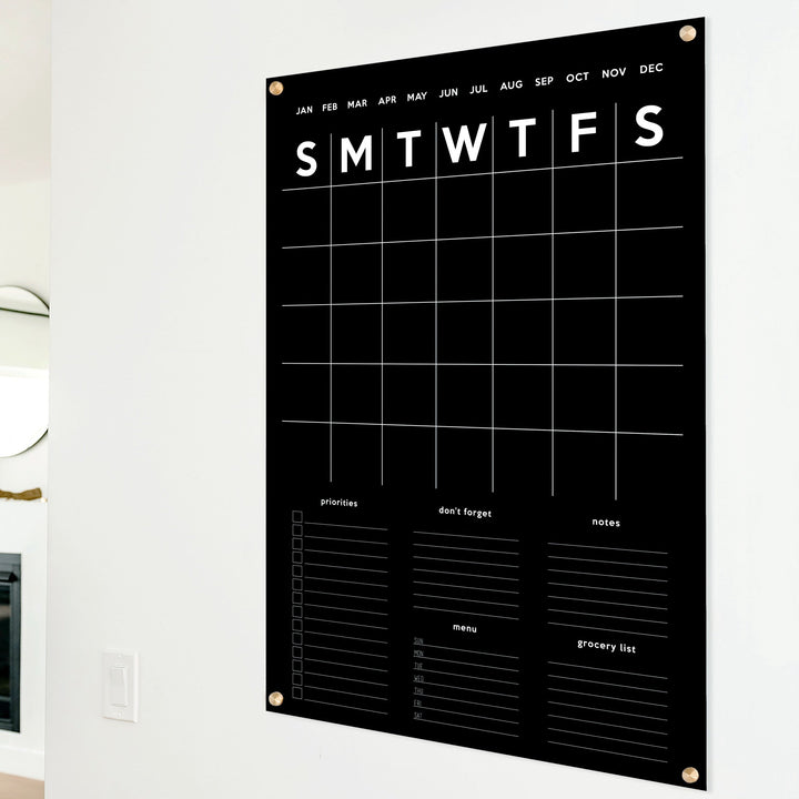 A Dry-erase family command center made of acrylic hanging on the wall