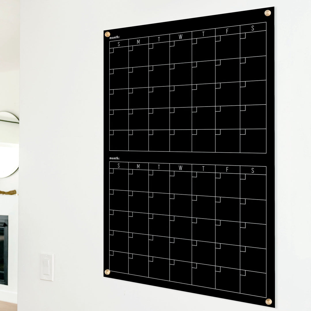 A Dry-erase acrylic calendar with a two month design format hanging on the wall