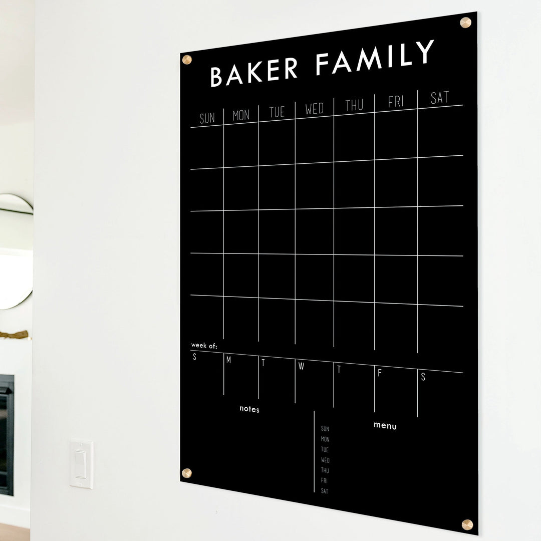 A Dry-erase calendar with a monthly and weekly format made of acrylic hanging on the wall