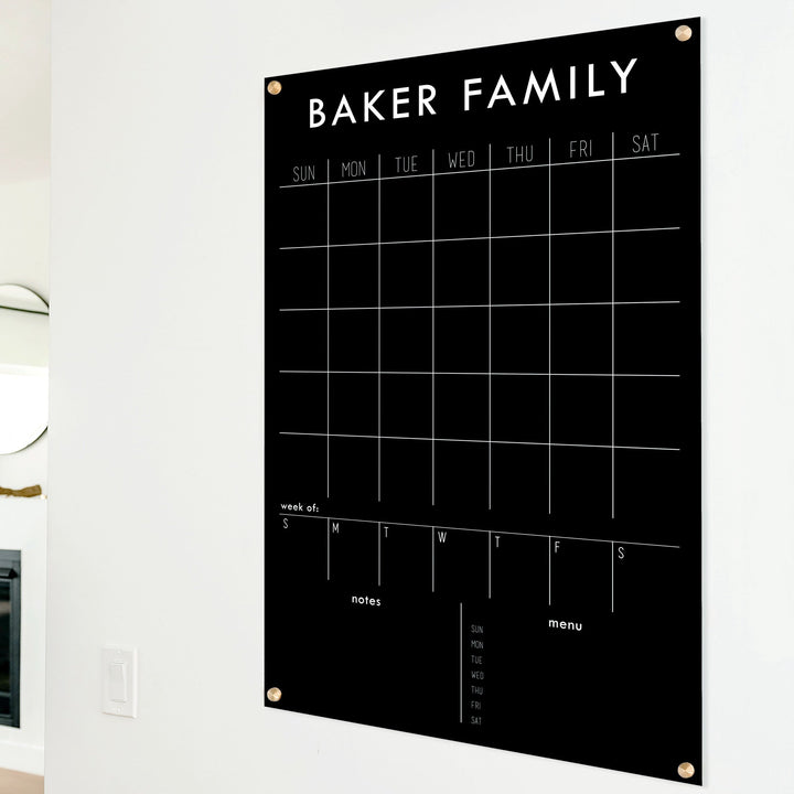 A Dry-erase calendar with a monthly and weekly format made of acrylic hanging on the wall
