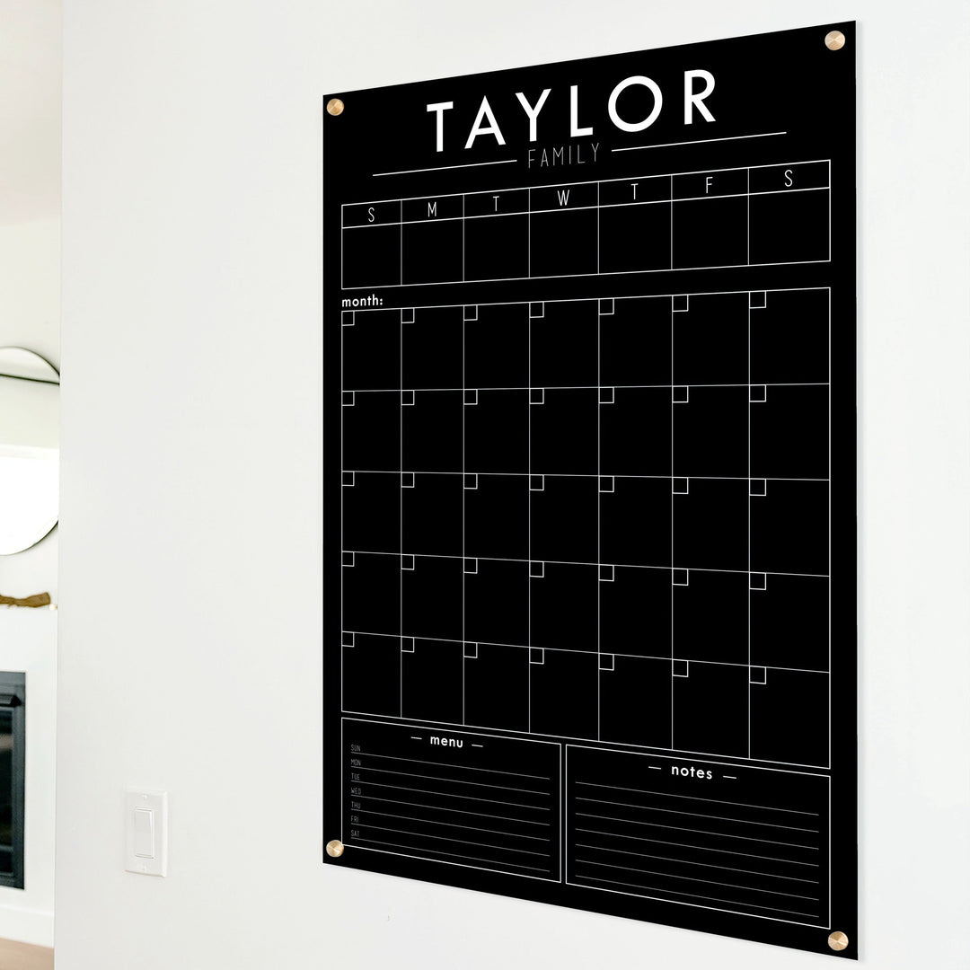 A Dry-erase calendar with a monthly and weekly format made of acrylic hanging on the wall