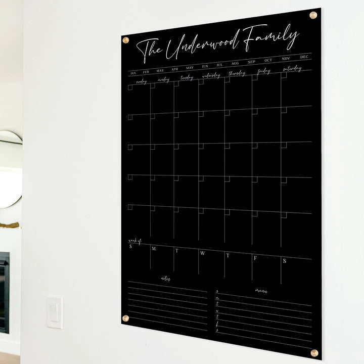 A Dry-erase calendar with a monthly and weekly format made of acrylic hanging on the wall