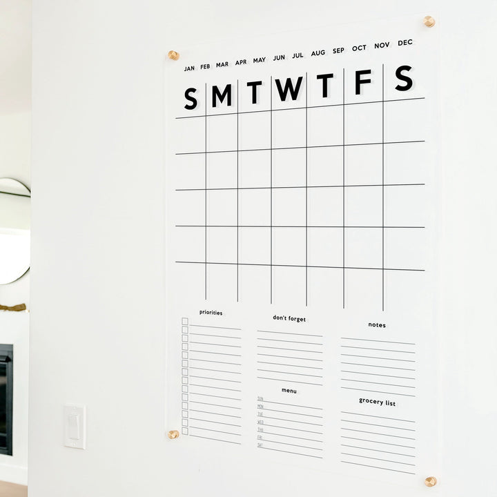A Dry-erase family command center made of acrylic hanging on the wall